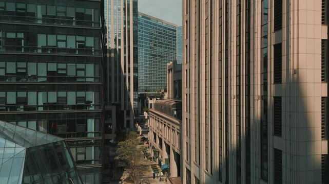 Upward aerial movement beside a tall modern building, revealing danse urban architecture in a Chinese city.