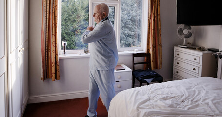Senior man stretching in home bedroom, relax and body health in the morning. Elderly person...