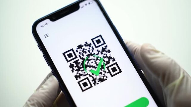 A person is using a smartphone to scan a QR code. Their gloved hand holds the device as the scanning interface displays a loading message. The background is clean and minimalistic.
