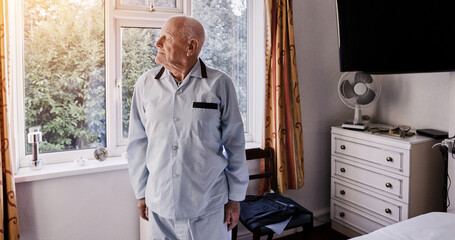 Window, thinking and senior man in bedroom for wake up, start and getting ready for the day. Retirement home, morning and elderly person with nostalgia, reflection and memory looking at view in room