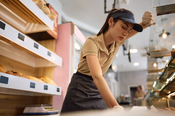Exhausted female worker with eyes closed in bakery.