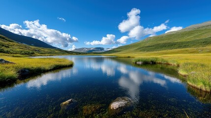 Fototapeta premium Scenic view of tranquil lake surrounded by lush green hills and vibrant blue sky.