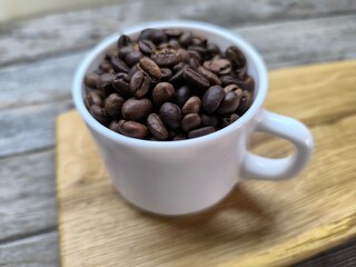 White cup with coffee beans on cutting board