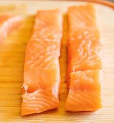Close-up of fresh raw salmon fillets placed on a wooden cutting board