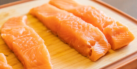 Close-up of fresh raw salmon fillets placed on a wooden cutting board