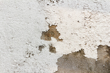 The white cement wall surface is peeling, dirty, old
