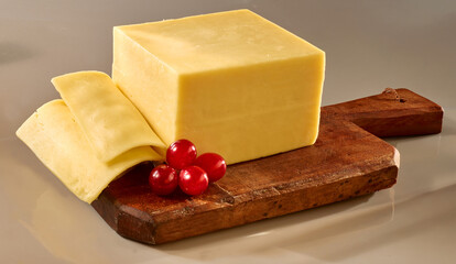 Butterkaese Stueck mit Scheiben auf rustikalem Holzbrett, Käse, Frühstück, 
