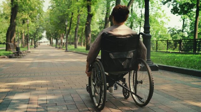 Senior woman with disability riding wheelchair in park, part of rehabilitation