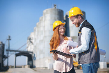 Two young managers talking in front of silo © Aleksandar