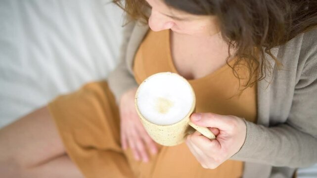 Mom-to-be savoring warm coffee drink in peaceful home setting. Responsible caffeine intake discussion during gestation period.