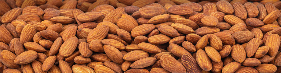 Close up of almond pile, Background of big raw peeled almonds, Long banner format. top view