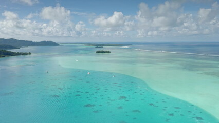 Stunning aerial view showcasing Bora Bora's mesmerizing turquoise lagoon, vibrant coral reefs, and lush green islands under a picturesque cloudy sky, creating a breathtaking tropical paradise