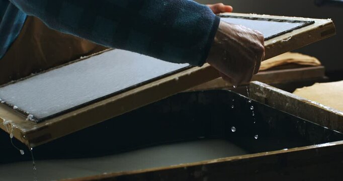 Super Slow Motion of Lifting the Mould and Deckle After Paper Pulp Sheet Formation During Traditional Handmade Papermaking. Artisan at Work in Craft Studio Using Ancient Paper-Making Technique.