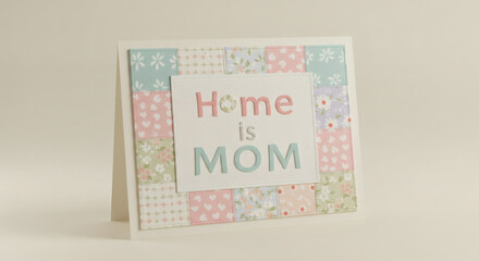Fototapeta premium A charming handmade card expresses 'home is mom' on a patchwork background, perfect for gifting.