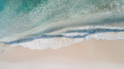 Blue sea sparkles and small waves crash against the beach with soft sand