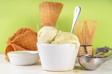 Matcha ice cream. Bowl with matcha green tea taste gellato with ice cream waffle cones. Vegan non-dairy summer dessert with matcha latte powder on top