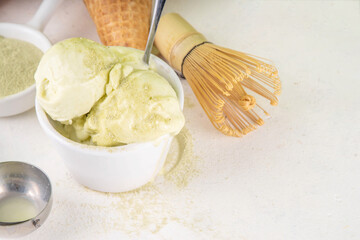 Matcha ice cream. Bowl with matcha green tea taste gellato with ice cream waffle cones. Vegan non-dairy summer dessert with matcha latte powder on top