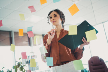 Young professional businesswoman surrounded by colorful sticky notes in a modern office interior