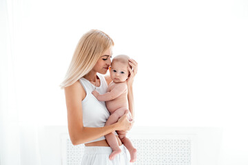 mom and baby hug and kiss, a young mother gently hugs a newborn baby girl holding her in her arms, maternal love and care, a young family, mother and daughter, a place for text