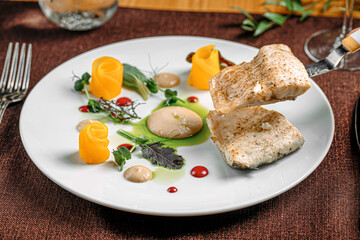 Portion of gourmet white fish dish with fruit slices and sauce