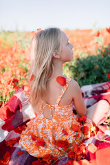 Child girl in blooming poppy field, summer day