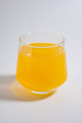 The image shows a clear glass filled with a vibrant orange liquid, likely juice or a beverage