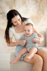 mom and baby, mother hugs and kisses baby holding him in her arms, maternal love and care, young mom having fun with baby baby, mom's decree
