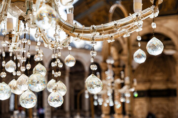 Vintage crystal chandelier hanging indoors, displaying intricate detailing and sparkling prisms....