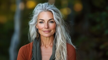 A captivating mature woman stands in nature, exuding confidence with long hair and a warm smile, revealing the beauty of aging gracefully and enjoying life.