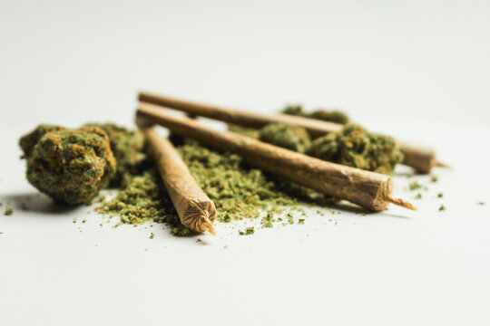 Close up of marijuana joint and buds on white background.