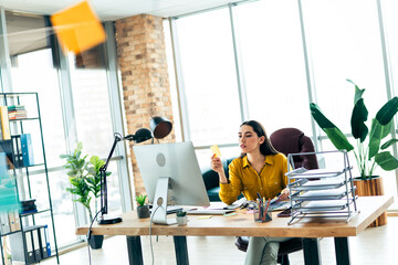 Young businesswoman managing tasks at a modern office desk during a productive workday, focused and...