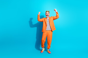 Fototapeta premium Charismatic mature man in vibrant orange suit joyfully celebrating success against vivid blue background expressing positivity