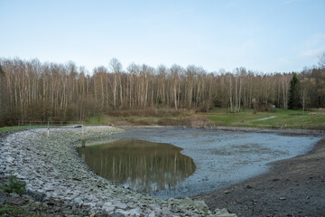 Drained pond with muddy bottom and rocky shore