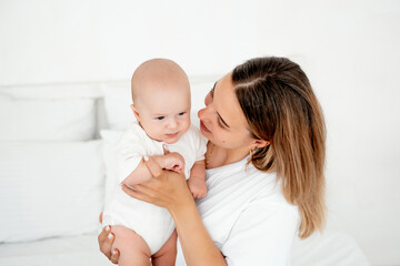 mom and baby, a young beautiful mother with a little boy hugging at home in the bedroom, maternal care and love, portrait of a happy mother with a child, healthy motherhood.