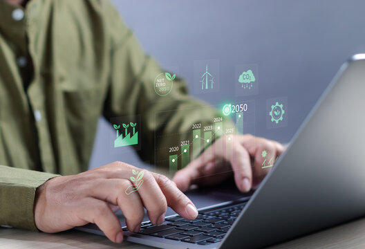 Environmental and sustainability concept, businessman working with computer analyzing data with environment impact, renewable energy, air pollution reduction targets and carbon emissions with graph