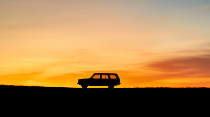 Fototapeta premium Silhouette of a vehicle against a colorful sunset sky on a horizon line.