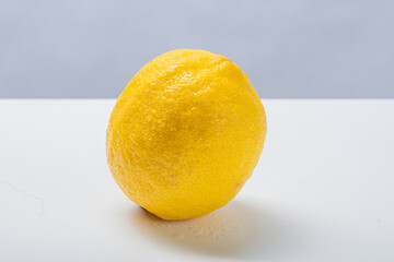 Whole and halved yellow lemons placed on a white surface with bright background, showing juicy citrus texture, seeds, and vibrant natural color of fresh tropical fruit