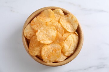 Tasty potato chips in bowl on white marble table, top view