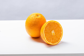 A juicy half orange stands upright on a clean white surface, revealing its vibrant, detailed pulp...