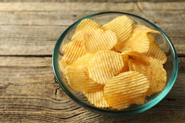 Tasty potato chips on wooden table, closeup