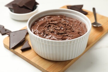 Tasty chocolate pudding in bowl served on white table, closeup