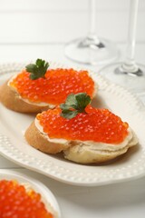 Tasty sandwiches with red caviar on white wooden table, closeup