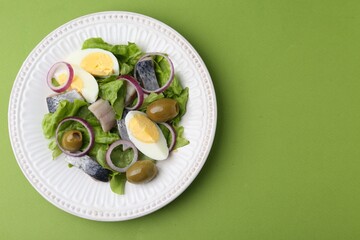 Delicious salad with herring, egg and vegetables on green background, top view. Space for text