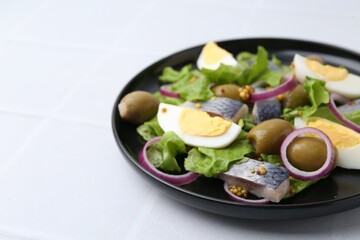 Delicious salad with herring, egg, mustard and vegetables on white tiled table, closeup. Space for text