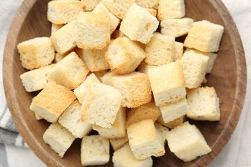Tasty crispy croutons in bowl on table, top view.