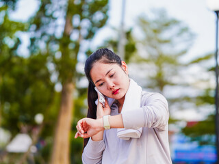 Fototapeta premium Asian fitness woman looking smartwatch data tracking exercise in nature park holiday. Motivation energy activity workout and healthcare. Wellness Lifestyle female of Southeast Asia work life balance 