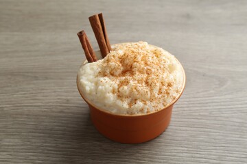 Delicious rice pudding with cinnamon in bowl on wooden table, closeup
