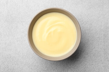 Tasty vanilla pudding in bowl on light grey table, top view