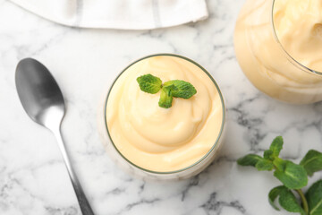 Tasty vanilla pudding with mint served on white marble table, flat lay