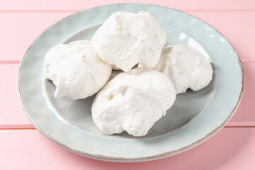 Delicious homemade meringue cookies on pink wooden table, closeup